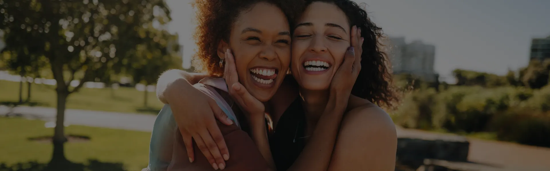 Two friends hugging and laughing in the sun