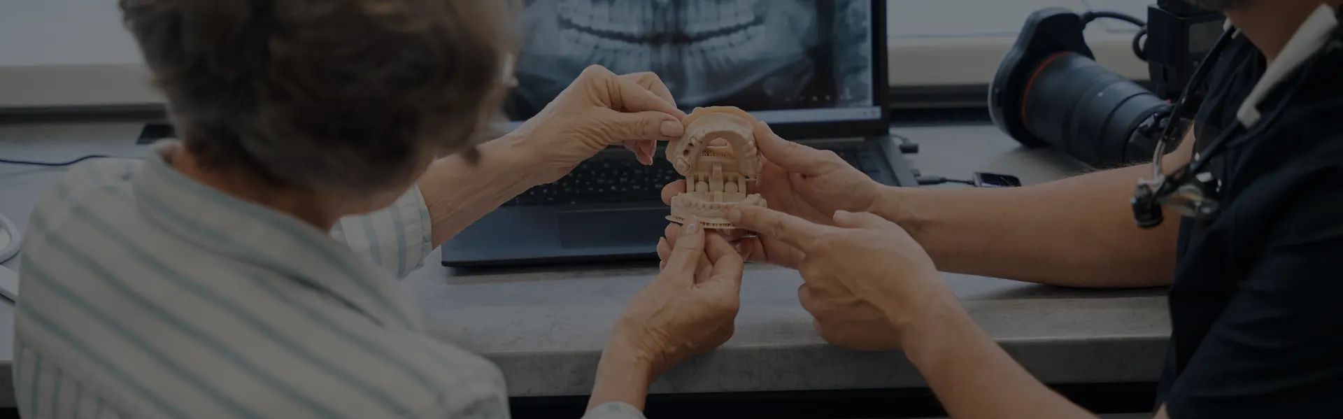 Dentist and patient looking at a dental model beside an X-ray