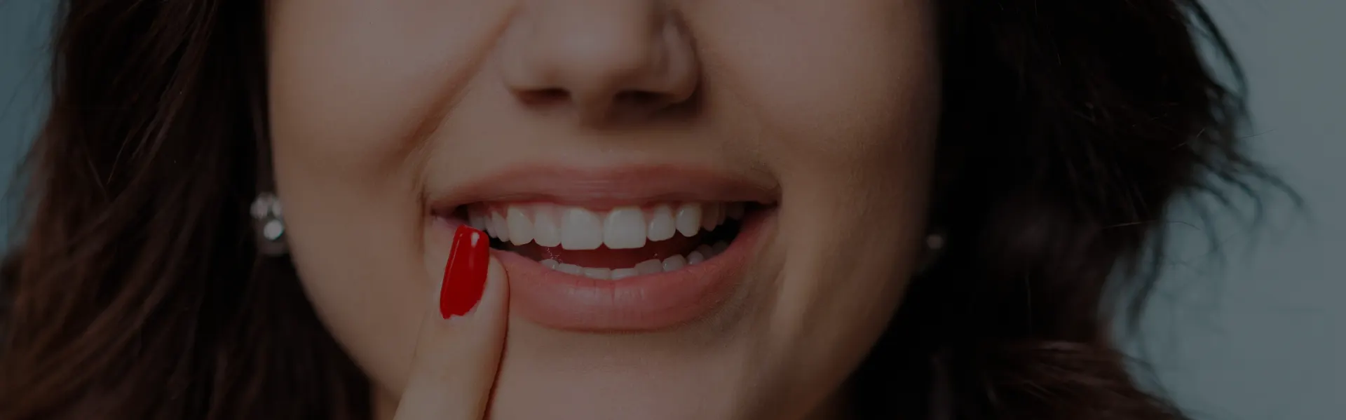 Woman with red nail varnish touching her smile