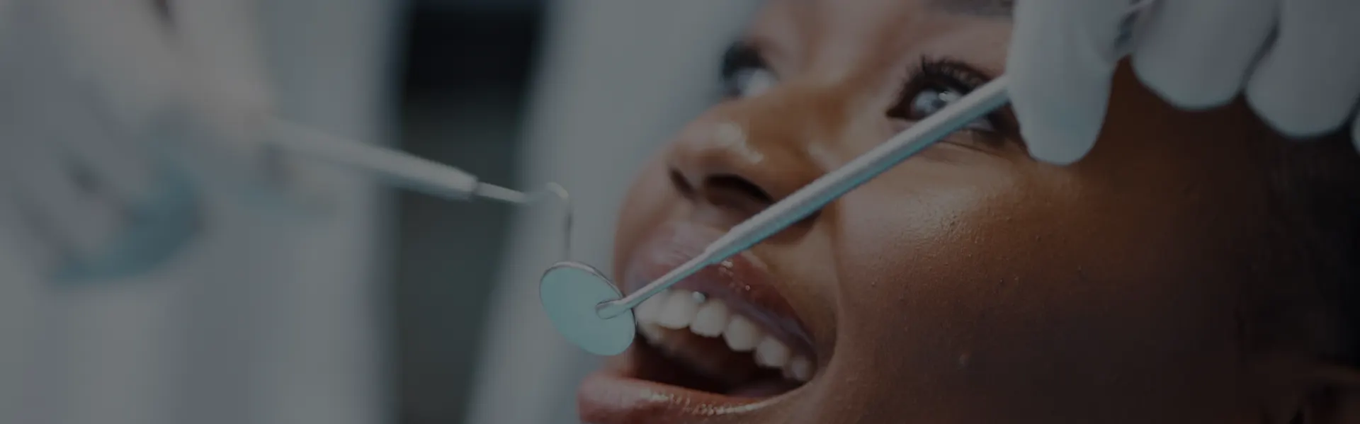 Dentist examining a smiling patient with a mirror