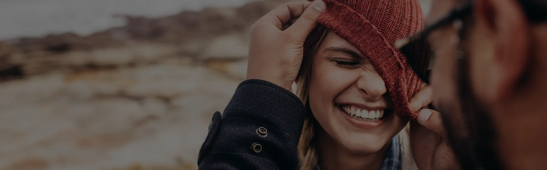 Young woman laughing with a woolly hat pulled over her eyes